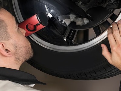 A certified Honda mechanic is inspecting the tire from under the vehicle. // Un mécanicien Honda certifié inspecte le pneu sous le véhicule