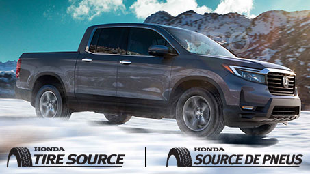 A grey 2021 Honda Ridgeline set against a cloudy blue sky and mountain range, driving effortlessly across snowy terrain. 	Un Honda Ridgeline 2021 gris sur fond de ciel bleu nuageux et de chaîne de montagnes, roulant facilement sur un terrain enneigé.