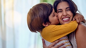 A little boy kisses his mother on the cheek. / Un petit garçon embrassant sa mère sur la joue.