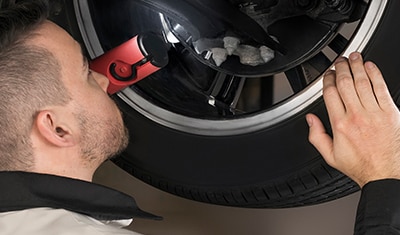 Gros plan d'un technicien certifié Honda inspectant la roue d'un véhicule.