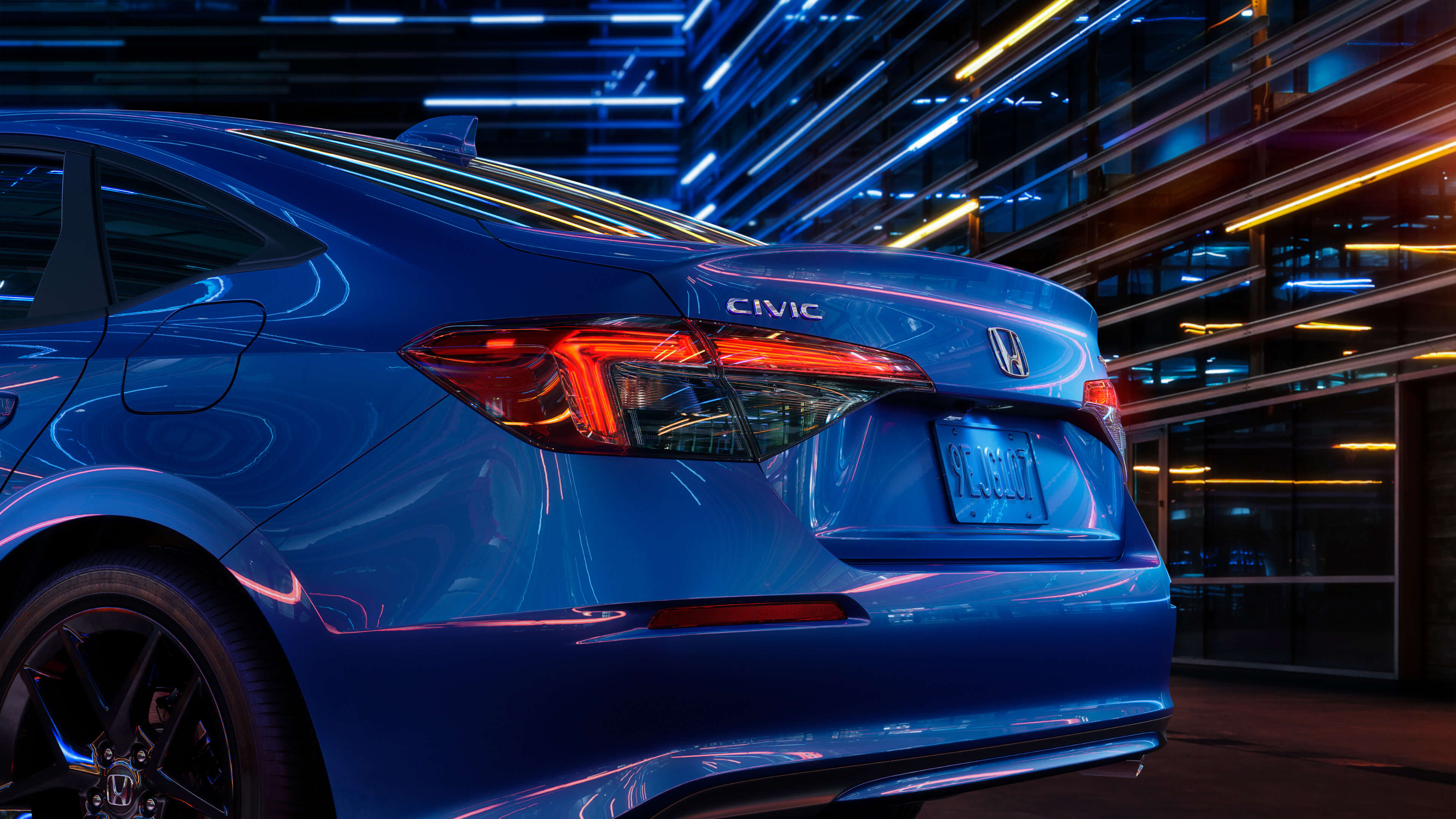 Side angled rear end view of a blue 2022 Honda Civic at night in a city.