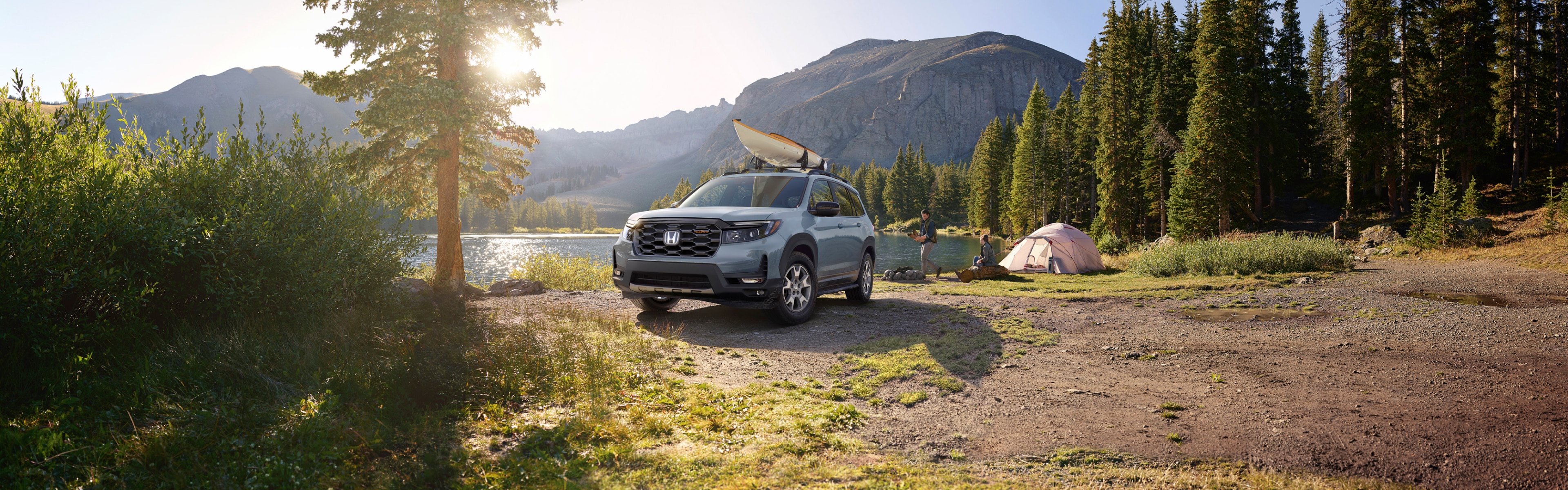 Front 3/4 view of 2021 Honda Passport Touring in Modern Steel Metallic parked at a campsite next to a lake.