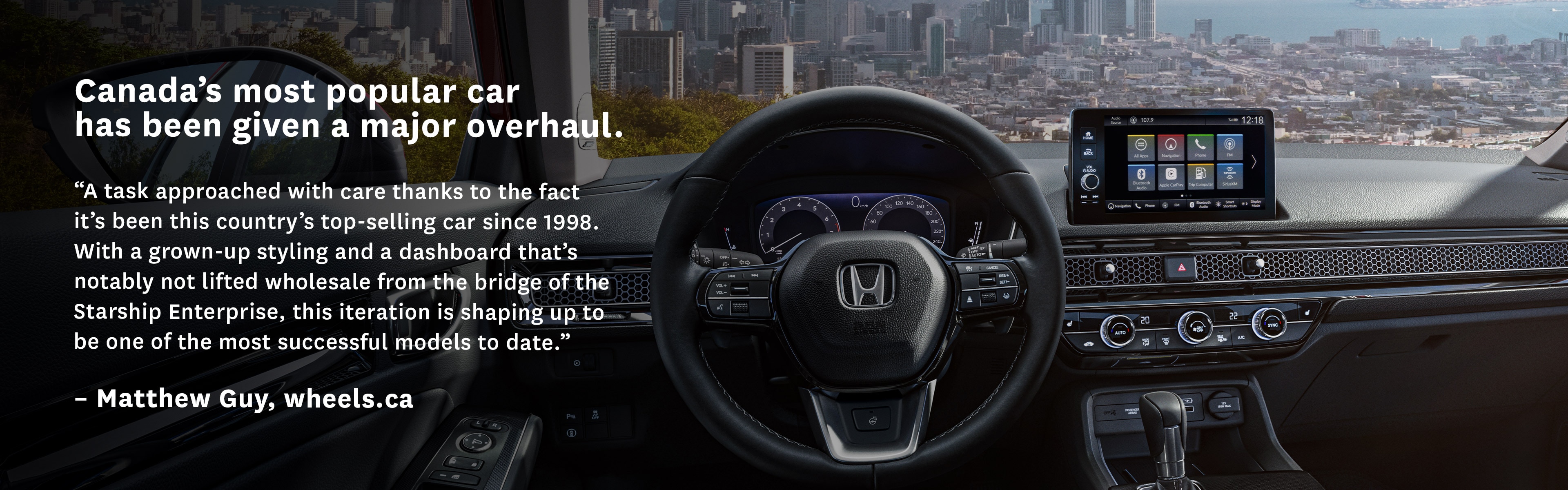 Interior cockpit of a 2022 Honda Civic from the driver’s point of view. The shot overlooks a city on a bay as seen through the windshield from atop a peak.