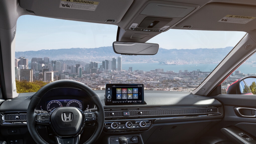 Cropped-in image of a 2022 Honda Civic windshield from the driver’s point of view. The scene through the window overlooks a city on a bay.