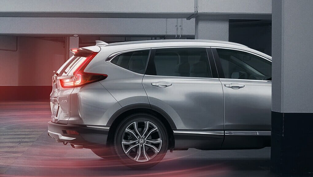 Passenger-side profile view of 2021 Honda CR-V Touring in Lunar Silver Metallic in parking structure.