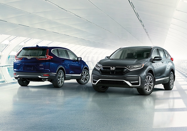 Front passenger-side view of the 2021 CR-V Touring in Modern Steel Metallic, driving across a bridge.