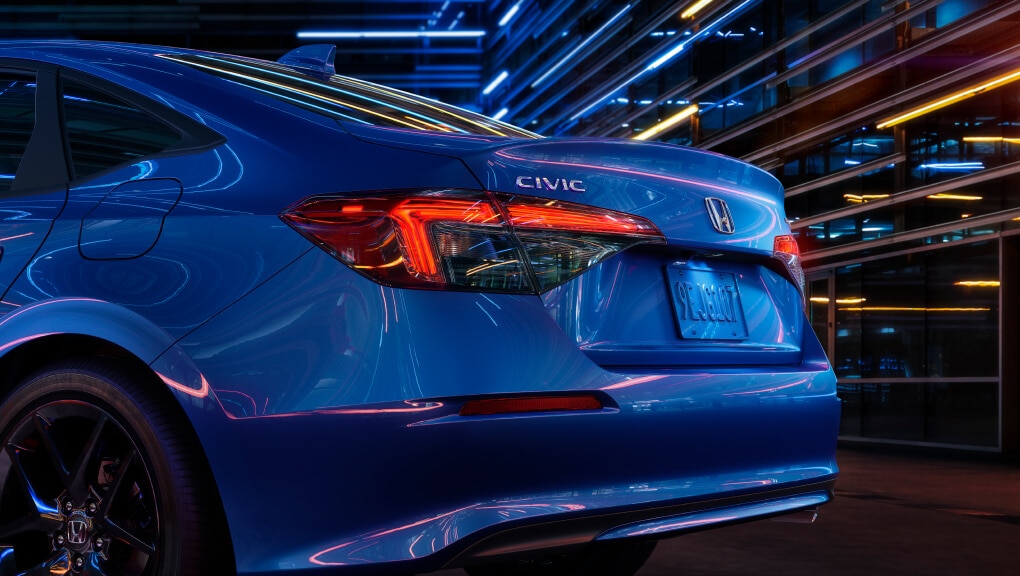 Side-angled rear end view of a blue 2022 Honda Civic at night in a city.