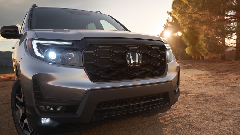 Front view of 2021 Honda Passport with active LED headlights at dusk.
