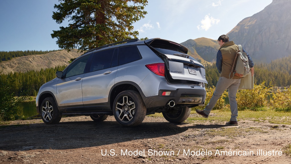 Rear 3/4 view of 2021 Honda Passport being opened via the available hands-free power tailgate.