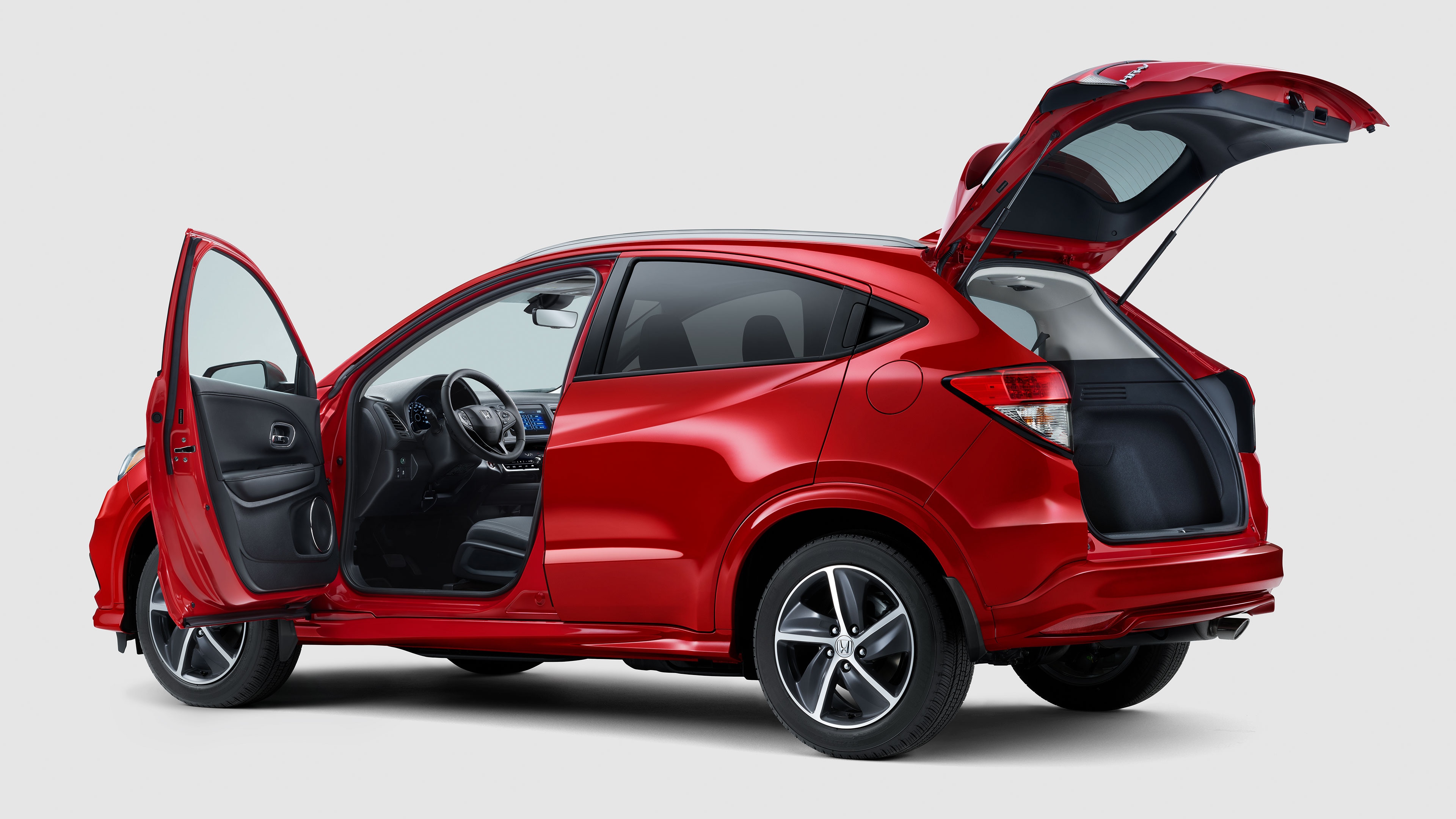 Rear driver-side view of the 2022 Honda HR-V Sport in red with driver door and trunk open.