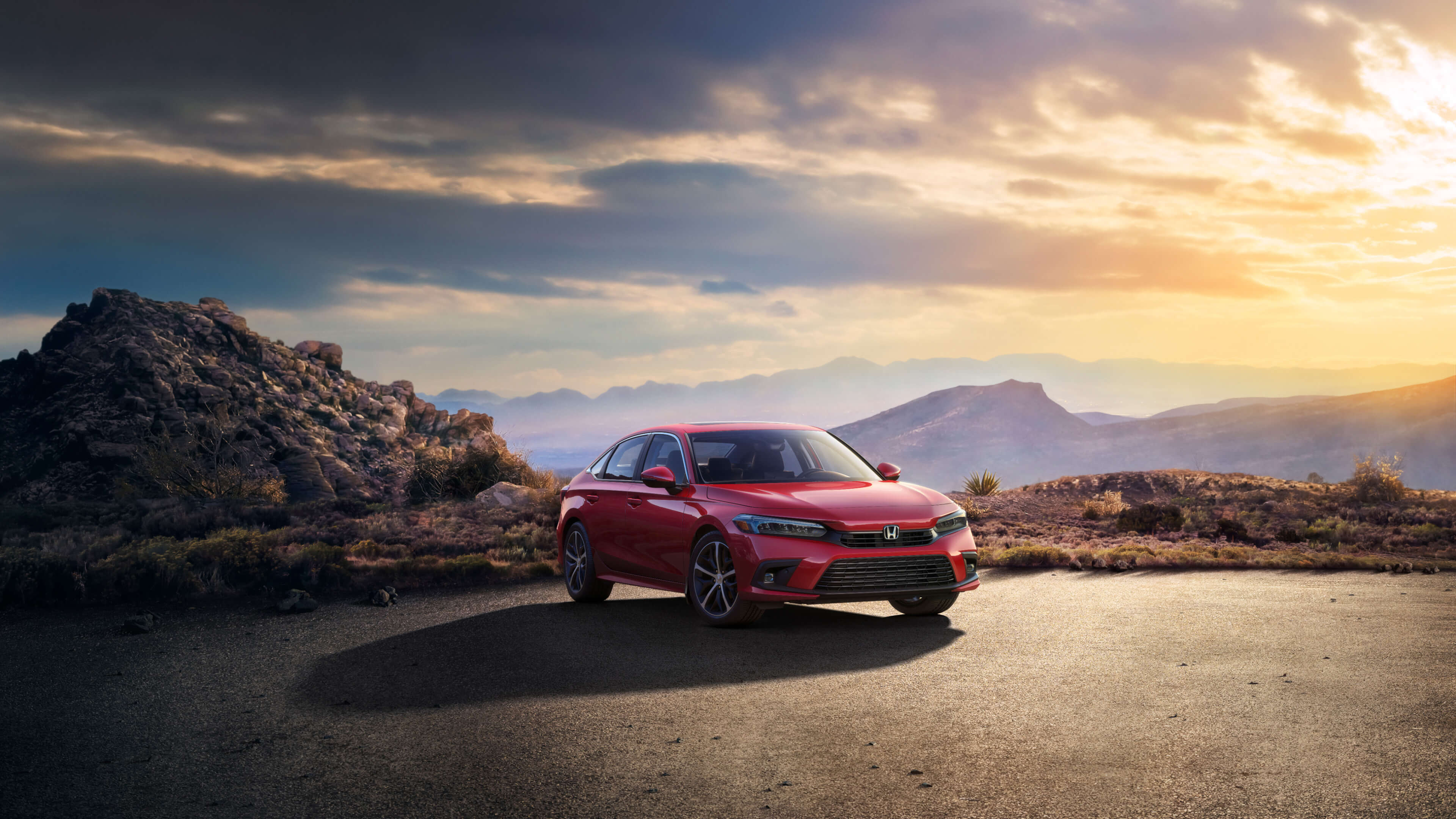 Front passenger-side, angled view of a red 2022 Honda Civic parked on asphalt with desert mountains in the background.