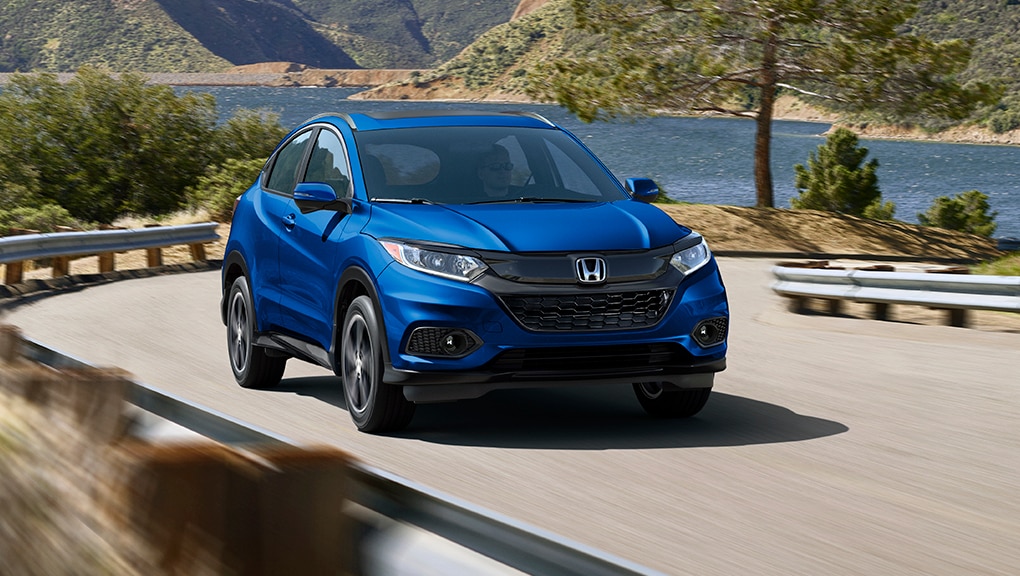 Front driver-side view of the 2022 Honda HR-V in silver driving on highway overlooking an ocean. 