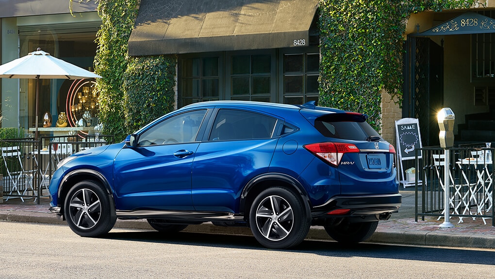 Rear driver-side view of the 2022 Honda HR-V Sport in blue parked in front of a café. 