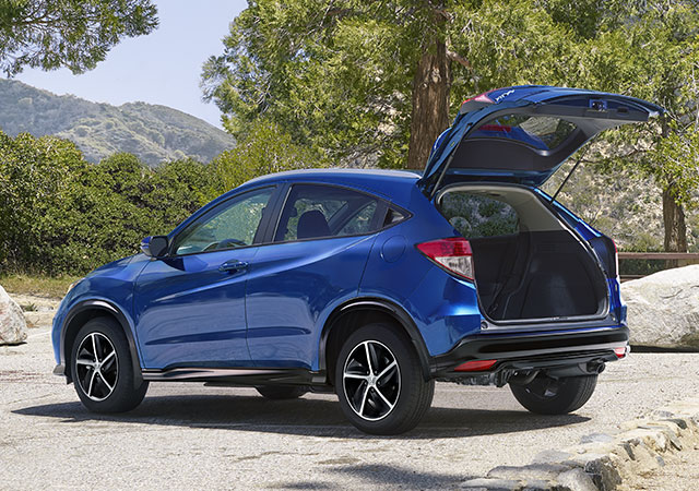 Rear driver-side view of the 2022 Honda HR-V Sport in blue with rear tailgate open, parked in mountain location. 